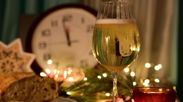 a champagne being poured into a glass at a festive New Year's Eve table setting, with a clock approaching midnight visible through the liquid's refraction.