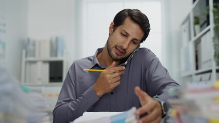 Exhausted worker in a busy office, multitasking with mobile technology and paperwork, grappling with the demands of his job while feeling overwhelmed.
 - Powered by Adobe