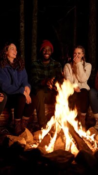 Young friends laughing around campfire night sharing warm stories and joyful moment. friends laughing around warm campfire night forest cozy