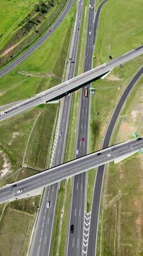 Rodovia com tr&aacute;fego organizado de ve&iacute;culos, destacando pistas paralelas, viadutos e a din&acirc;mica do transporte terrestre.