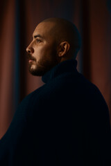 Moody side profile portrait of a man with a beard, softly lit against a textured background. The image conveys introspection, strength, and contemporary masculine elegance. © Francis