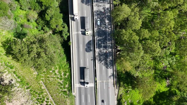 Vis&atilde;o a&eacute;rea de rodovia com tr&acirc;nsito de ve&iacute;culos em m&uacute;ltiplas faixas, destacando mobilidade regional, infraestrutura vi&aacute;ria moderna e fluxo cont&iacute;nuo de transporte.