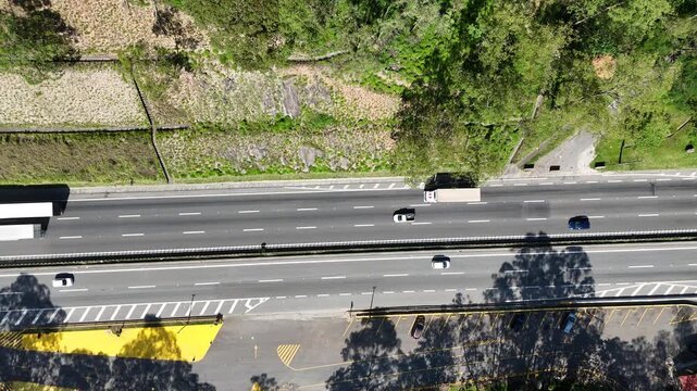 Imagem a&eacute;rea de rodovia com ve&iacute;culos em movimento, evidenciando o fluxo de tr&aacute;fego e a organiza&ccedil;&atilde;o da malha vi&aacute;ria.