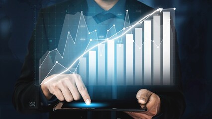 A businessman interacts with a digital tablet displaying financial charts and graphs, emphasizing data analysis and decision-making in a corporate setting. Copula