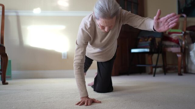 A senior woman practices yoga and morning exercises in her living room to stay flexible and fit daily.