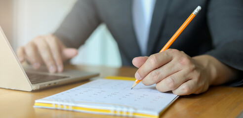 close up on businessman hand using pen to writing schedule on calendar to make appointment meeting or manage timetable each day at house for work from home concept