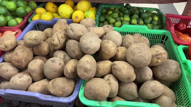 Fresh potatoes displayed in baskets alongside lemons and limes at a market