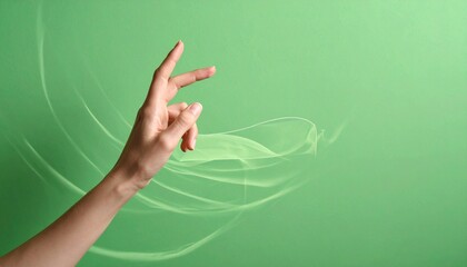 Woman's hand making a precise gesture, pinching or holding small object, on a vibrant green background with abstract swirling lines.