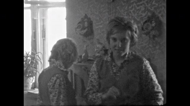 Young woman looking into camera in cozy rural home interior in analog footage. Candid moment of everyday domestic life. Simple countryside living. Old film. Archival retro 1970s. Vintage archive