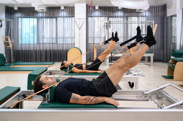 Men and women strengthen muscles to maintain physical health. Couple enjoying pilates classes in fitness studio.