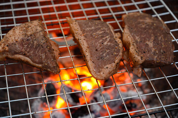 Grilled beef steak cooking on a charcoal fire. BBQ moments that bring people together.
