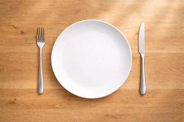 白い皿とカトラリーを並べた白木テーブルのフラットレイ　料理イメージ用背景