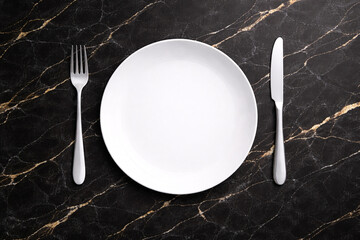 黒大理石のテーブルに白い皿とカトラリーを並べたフラットレイ　高級感のある食事背景