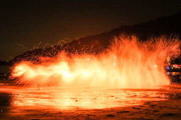 Explosive splash of fire sparks on the beach at night. Abstract long exposure of burning steel wool...