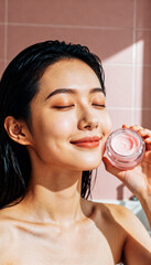 Blissful skincare routine with smiling young east asian woman using face cream