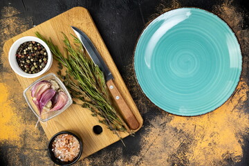 Cooking preparation with herbs, spices, and kitchen tools on wooden cutting board and turquoise plate