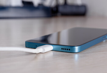 Smartphone charging on wooden surface.