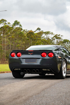 Gray Chevrolet Corvette C6 rear view on road, American sports car driving outdoors