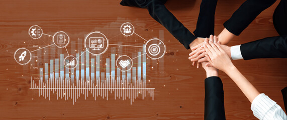 A diverse group of business partners joins hands over a wooden table, surrounded by digital graphs and icons symbolizing teamwork and analysis for success. Trope