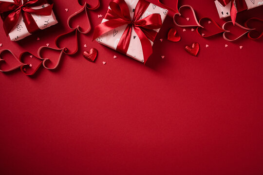Valentine's Day gifts and paper hearts on red background with copy space. - Powered by Adobe