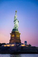 Fototapeta premium Statue of Liberty close-up at sunset. Close-up view of the Statue of Liberty with the sky lit in warm sunset tones.