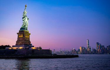 Statue of Liberty at twilight with Manhattan skyline. The Statue of Liberty at twilight with the Manhattan skyline glowing in the distance. © white78