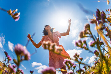 Summer mood. young and cheerful girl in summer dress posing against blue sky and flowers. beautiful girl dancing among flowers. girl enjoying summer.
