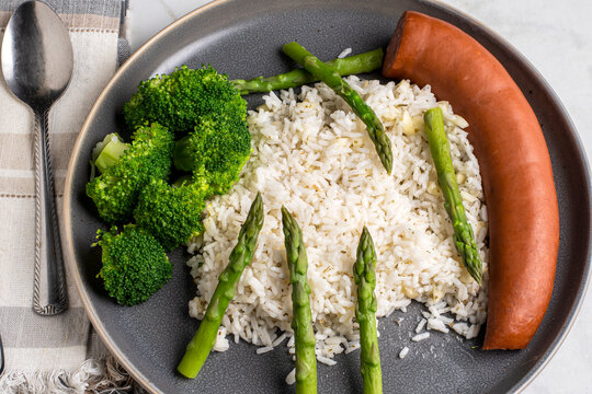 rice  top with asparagus served with broccoli and smoked sausage