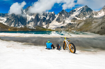 Cyclist Exploring a Glacial Mountain Lake Surrounded by Snowy Peaks