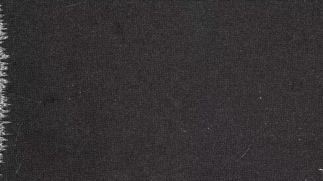 Dark woven fabric material with frayed edges and some minor imperfections