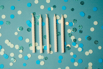 Celebratory candles placed on a vibrant blue background with confetti