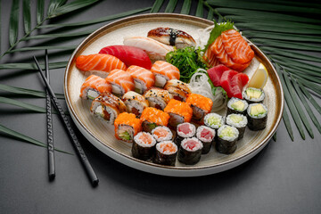 Variety Platter of Sushi, Sashimi, and Maki Rolls. A circular plate features a rich variety of nigiri, sashimi, and maki rolls, showcasing tuna, salmon, eel, and vegetable fillings. © white78