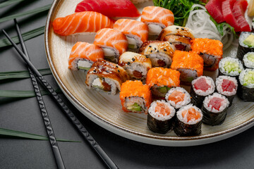 Variety Platter of Sushi and Maki Rolls on Plate. A large platter features a diverse assortment of fresh nigiri, sashimi, and maki rolls arranged elegantly on a textured plate. © white78