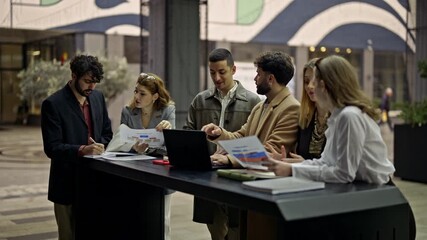 Young business people engage in a collaborative remote work session outdoors. They discuss project details, analyze documents, and utilize technology to strategize, embodying teamwork and innovation.