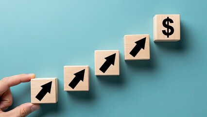 Hand placing wooden block with upward arrow on ascending step blocks leading to dollar sign on blue background