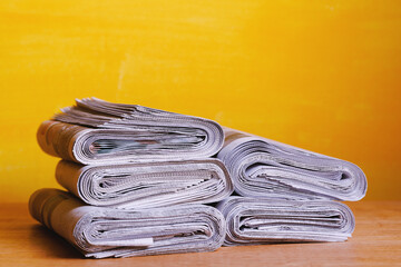 Newspapers folded and stacked on yellow background