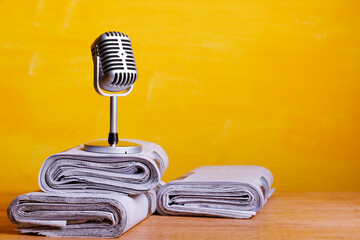 Retro microphone with newspaper on wooden table - announcement concept