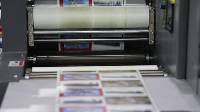 Automated printing. Industrial printing press in action with colorful rollers and sheets moving on automated production line. Modern offset printing technology. High quality mass print  manufacturing