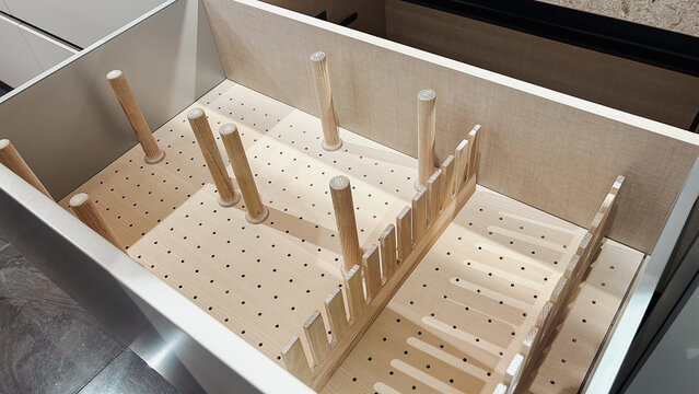 Clean empty kitchen drawer with light wood pegboard. Adjustable dividers for efficient storage organization.