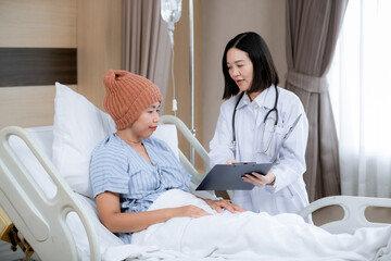 A female doctor uses a stethoscope to check a patient&rsquo;s heartbeat while she lies in a hospital bed, showing care, trust, and professionalism in a healthcare environment.