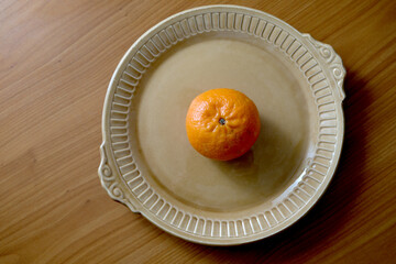 Bright orange fruit resting on a stylish plate in warm sunlight