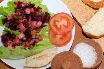 Colorful salad with vegetables and fresh bread on a wooden table