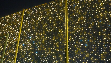 Flashing yellow and blue modern garlands of light bulbs in evening darkness. Theme of the New Year and Christmas. A background of sparkling light bulbs. Festive mood. Window and street decoration