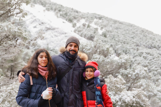 Bearded Father Aged Forty Posing with His Twelve Year Old Daughter and Ten Year Old Son in a Snowy Forest on a Winter Day