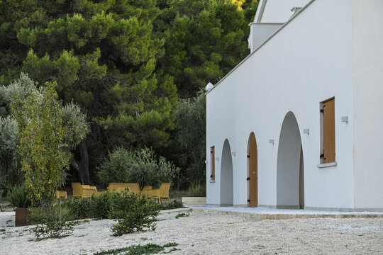 Traditional Mediterranean finca with whitewashed walls, terracotta roof, wooden shutters, and courtyard surrounded by natural stone, olive trees, and sunlit terraces. Rustic rural charm.