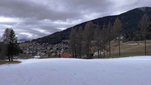 Spring Thaw in Mountains with Green Grass Appearing Through Melting Snow, Climate Change and Global Warming Concept, End of Winter Season in Ski Resort