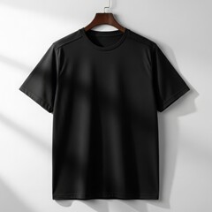 A plain black t-shirt hanging on a wooden hanger against a white wall, with soft shadows adding depth and realism.