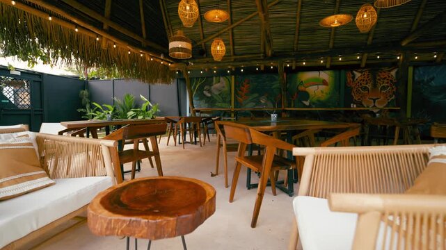 Cozy outdoor patio of a jungle themed restaurant or hotel. Rustic bamboo furniture and warm string lights creating a relaxing atmosphere