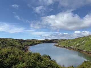 Fototapeta premium Sunny summer view of a sea loch on the Isle of Scalpay, showing calm coastal waters and a remote island landscape in the Outer Hebrides.