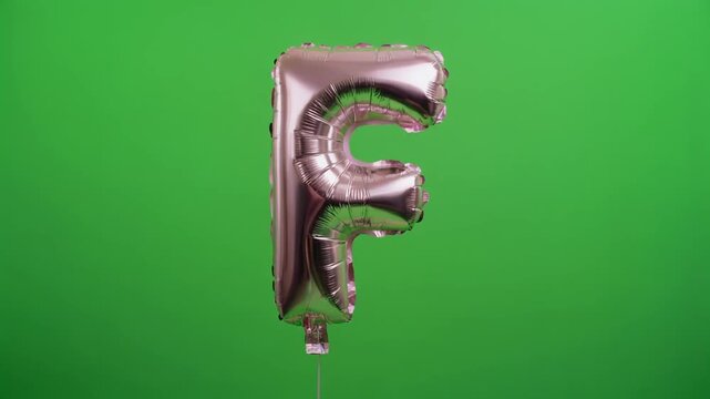 Pink Foil Balloon Letter F Floating on Green Screen Background.